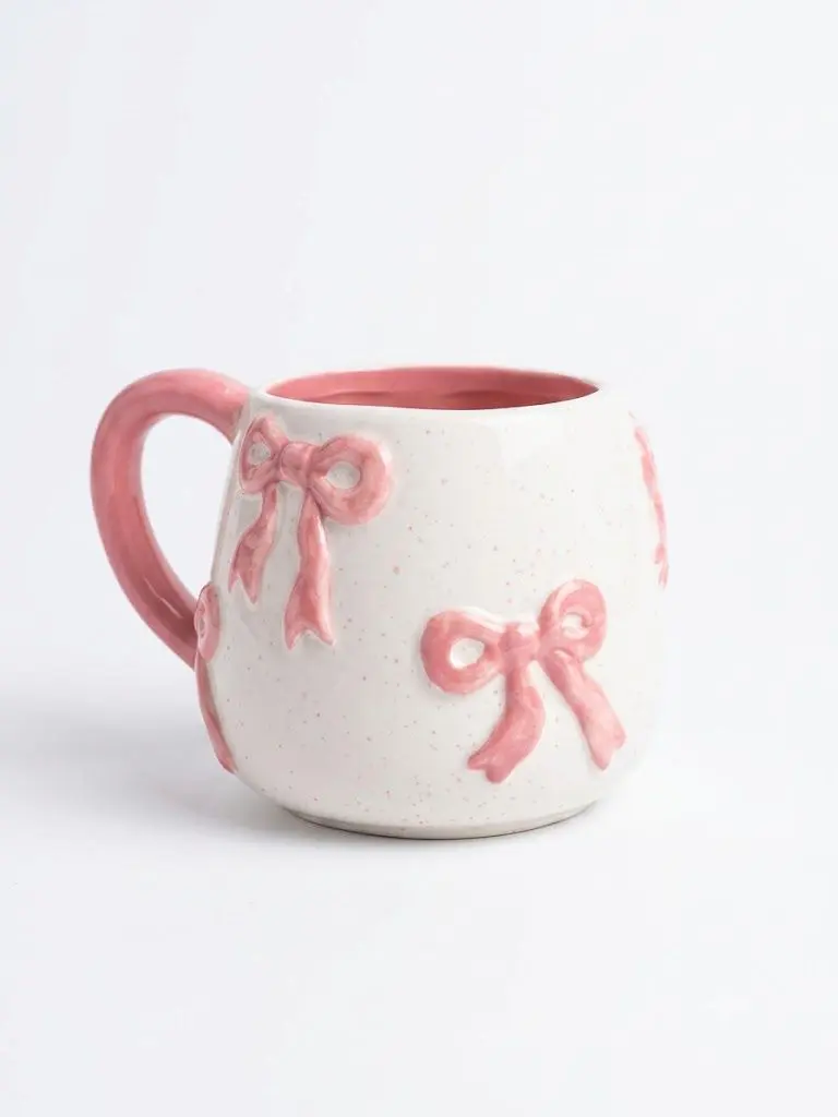 Ceramic mug with raised 3D bows and a pink dotted finish.