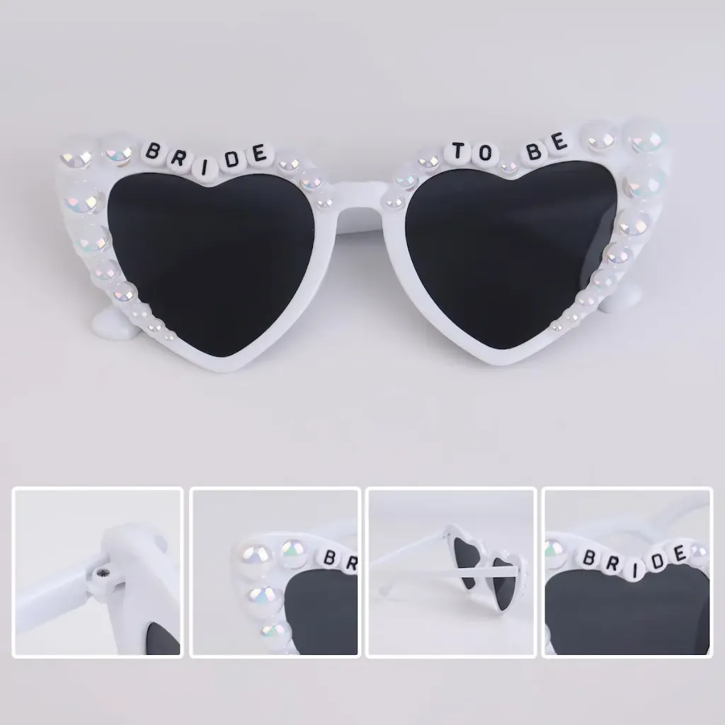 White heart-shaped sunglasses with pearl embellishments and "BRIDE TO BE" lettering on the frames.