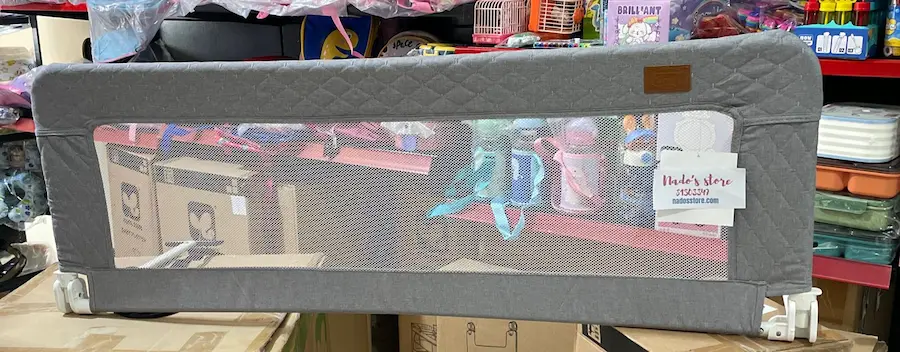Baby bed rail guard with a mesh center and quilted Gray fabric trim designed to prevent children from falling out of bed.
